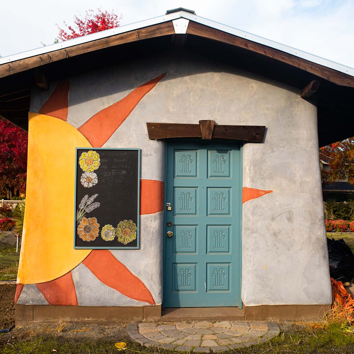 Garden shed with orange sun burst painted on left side