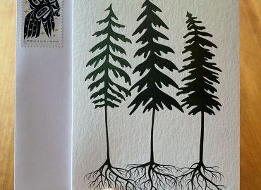 Three fir trees stand together with roots entwined on a gratitude card with envelope and raven stamp.