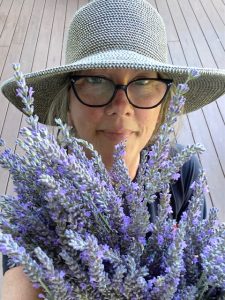Angie Windheim in sunhat looking over a bouquet of fresh lavender from her garden